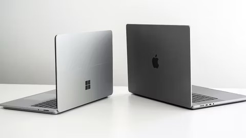 A Mac and a Windows Laptop Placed Side-by-Side on a White Surface  