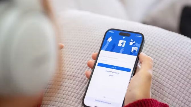 a person holding an iPhone with the facebook app